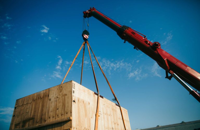 Ein Schwertransport-Kran hebt einen Holzcontainer in die Luft